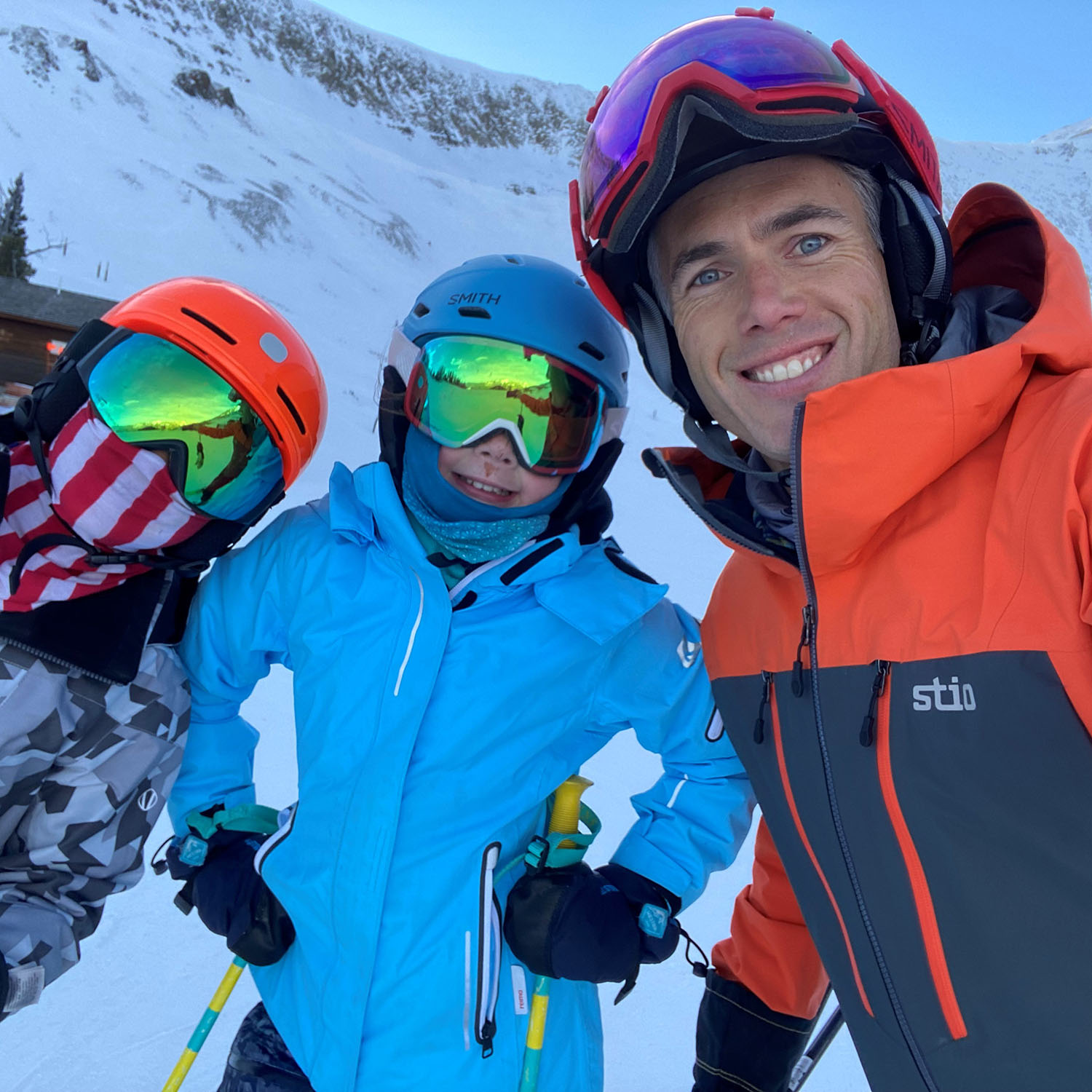 Director Matt Kid and two children smile at the camera while skiing